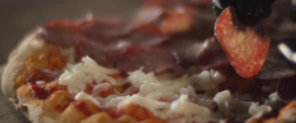 Close up of a chef placing pepperoni layer over cheese on traditional al taglio pizza.