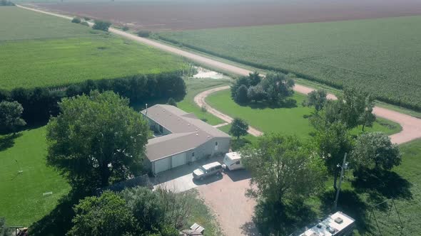 Drone aerial view of a sprawling home, farm yard, standing water, corn fields and a gravel road in r