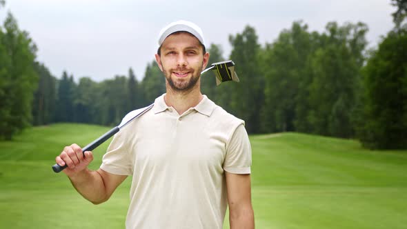 Young man with golf club looking at camera at golf course