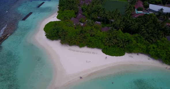 Tropical birds eye tourism shot of a sandy white paradise beach and aqua blue water background in co