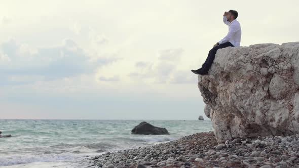 Handsome Stylish Man Sitting on the Rocks and Watching an Amazing View