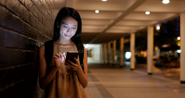 Woman using mobile phone in city at night 