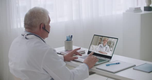 Therapist and Infectious Diseases Specialist Are Consulting Each Other By Video Call From Offices in