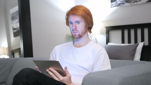 Redhead Man Browsing Internet on Tablet PC, Sitting on Couch