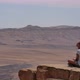 Young Woman in Sunglasses Sitting on Cliff's Edge and Looking Around the Desert - VideoHive Item for Sale