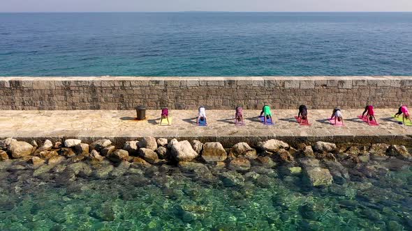 Aerial view of group practicing yoga at artificial pier, Veli Losinj, Croatia.