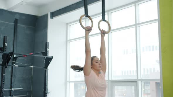 Young Woman Training Abdomen Muscles on Still Rings Working Out During Intense Crossfit Practice