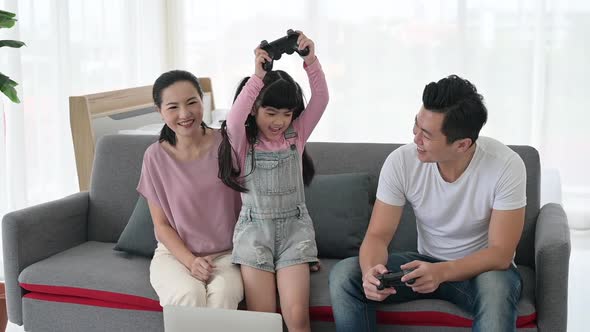 The daughter, father and mother were playing video games and having fun at home