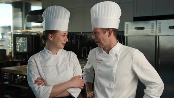 Professional kitchen, portrait: Female and Male Chef stand side by side in the kitchen