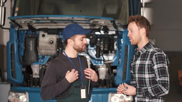 Young Automotive Technician Talking with Male Client