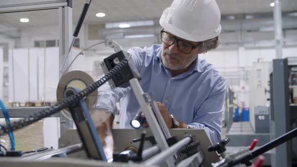 Focused Mature Factory Technician Wearing Hardhat