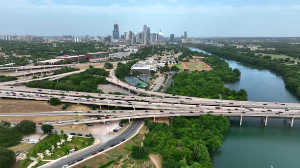 Wide aerial reveals interstate highway freeway traffic with Austin Texas skyline in distance. Commut