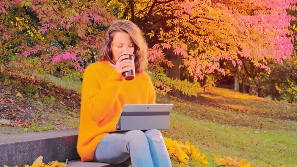 Beautiful Woman Working with Laptop and Enjoying Autumn in Park