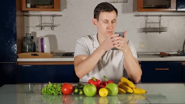 Man Looks for Salad Recipe Sitting Near Fresh Vegetables