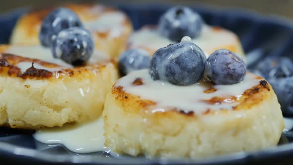 Cheesecakes From Cottage Cheese in a Blue Bowl Poured with Condensed Milk