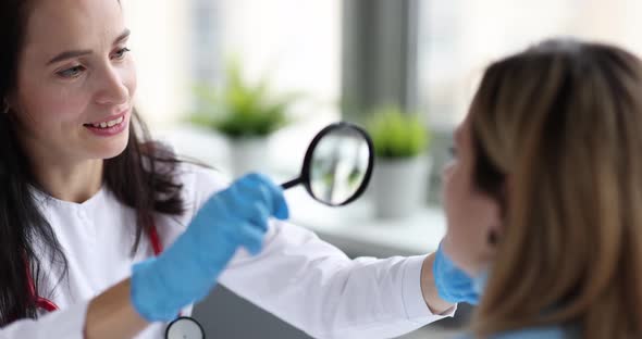 Doctor Cosmetologist Examining Skin of Patient Face with Magnifying Glass  Movie Slow Motion