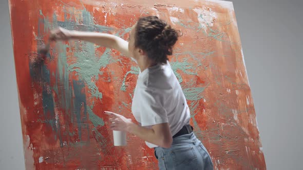 Woman Artist Draws with a Brush on a Large Canvas in a White Room a Talented Artist Draws a Color