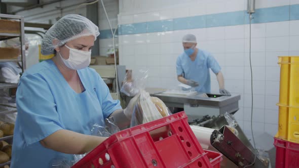 An Employee Working in a Bakery. The Baker Spreads the Sliced Bread on an Automatic Packaging