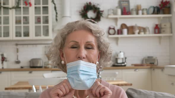 Portrait of an Elderly Woman Removes a Medical Mask Looks at the Camera and Smiles Closeup