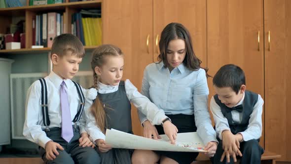 Elementary School Pupil and Teacher Discussing Picture with Classmates