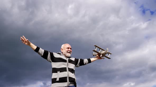 Happy Elderly Man Pretend Flying on Model Aircraft in Sky Dream