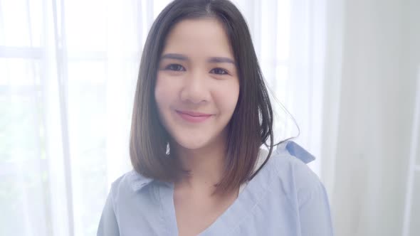 Asian Chinese woman feeling happy smiling   looking to camera while lying bed in bedroom.