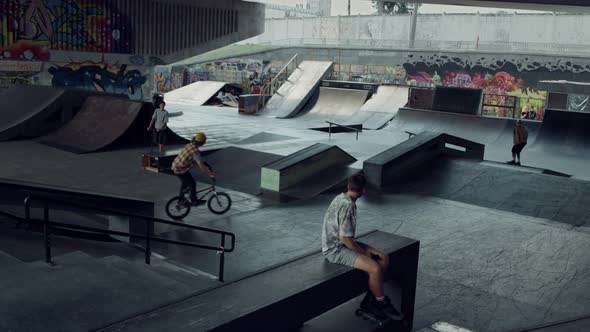 Sporty Teenagers Spending Time Together at Urban Skate Park with Graffiti