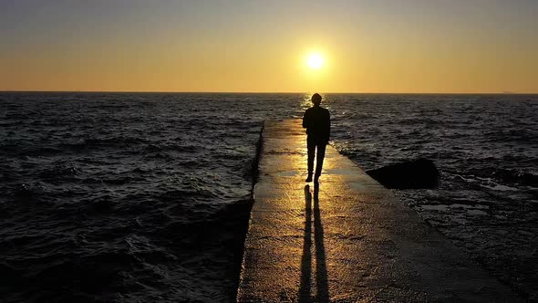 Slow motion female walking by the ocean with waves on sunset