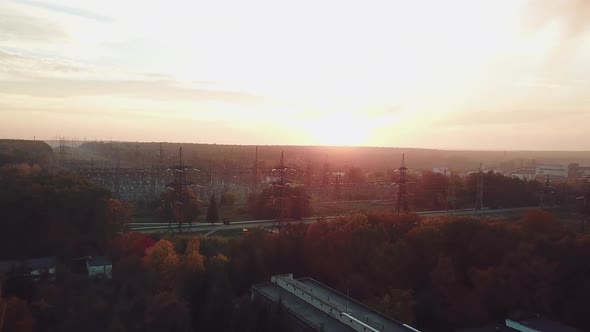 view of the site with high voltage lines on the background of the road and trees at sunset.