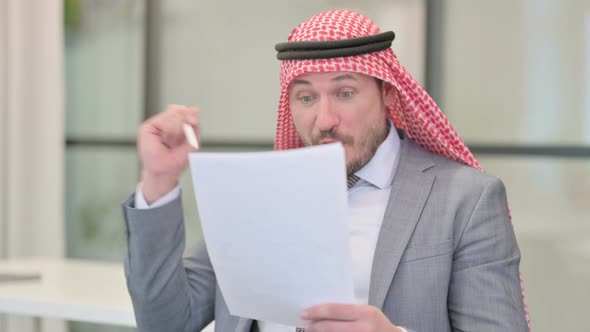 Middle Aged Arab Businessman Celebrating Success while Reading Documents in Office