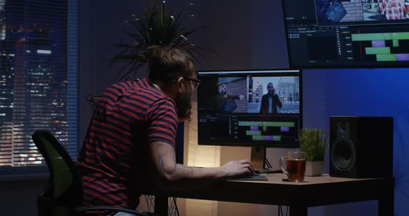 Young Man Sitting Back and Editing Video Inside a Room