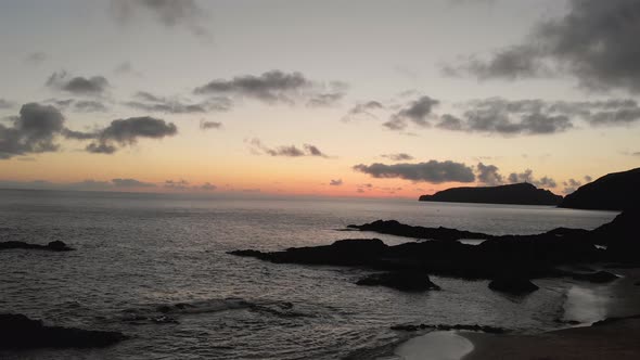 Spectacular sunset flight above Calheta sandy beach toward beautiful ocean sea water, rock outcroppi