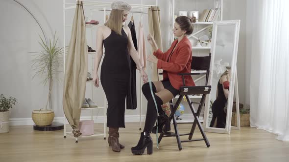 Wide Shot Portrait of Young Tailor or Seamstress Measuring Hands of Stylish Female Client in Atelier