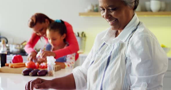 Smiling grandmother holding recipe book in kitchen 4k