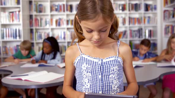 Schoolgirl using digital tablet in library