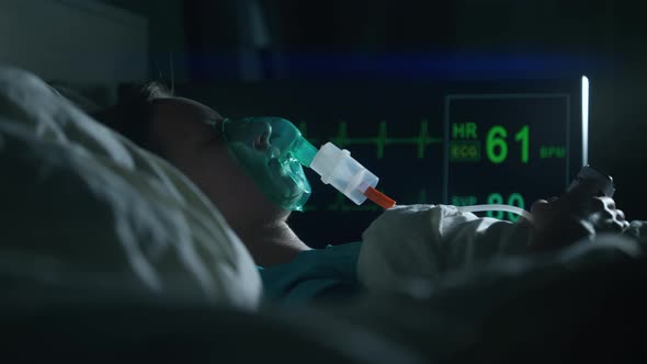 A Female Patient in Medical Mask is Breathing Oxygen Support in a Hospital Next to Heart Rate