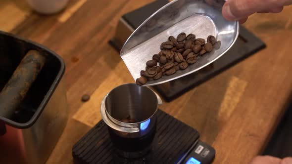 Weighing roasted coffee beans on a scale to prepare a sample drink at a roastery, Handheld close up