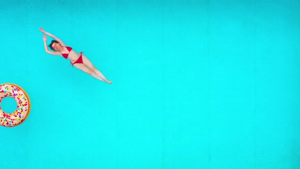 View From the Top As a Woman in a Red Swimsuit Lying on Her Back in the Pool