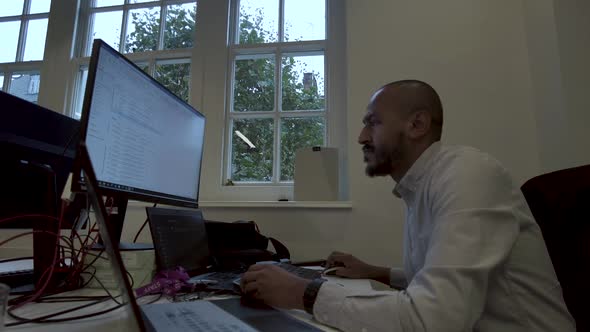 Young Asian Indian man busy work multiple screen computer or smart tablet on table desk at home in f