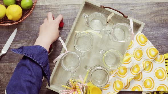 Step by step. Pouring raspberry lemonade with fresh lemons and raspberries in drinking mason jars.