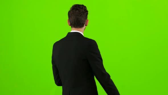 Guy Walks Down the Street, Puts His Hand in His Pocket and Waves. Green Screen. Back View