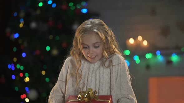 Girl Hugging Warped Gift Box, Long-Awaited Christmas Present, Dreams Come True