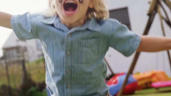 Happy boy with face paint jumping in backyard 4k