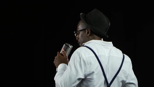 Man Singer the View From the Back Sings Into a Microphone and Dance. Black Background. Close Up