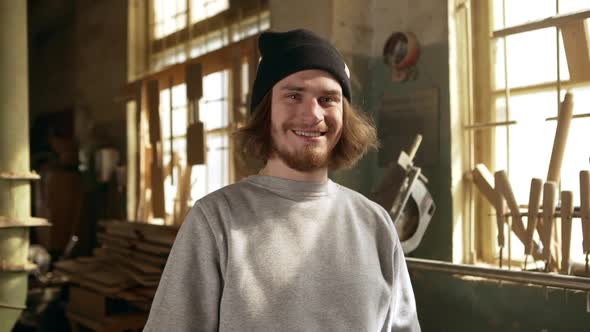 Happy Young Male in Black Sock Cap and Ginger Beard Laughing at Camera Standing in Joinery