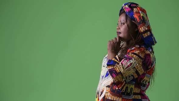 Overweight Beautiful African Woman Wearing Traditional Clothing Against Green Background