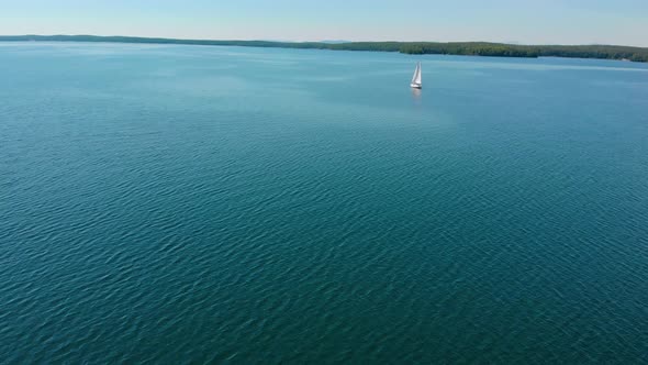 Aerial View of Sailing Boat Walking Alone on a Wide Blue Clear Lake on a Sunny Morning