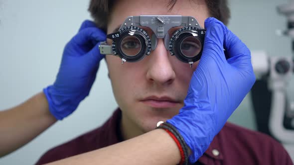 Doctor Hands Adjusting Lens in Trial Frame for Patient in Hospital Indoors