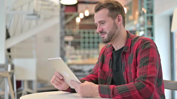 Professional Young Man Doing Video Chat on Tablet in Cafe