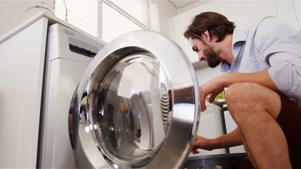 Man putting his clothes into washing machine